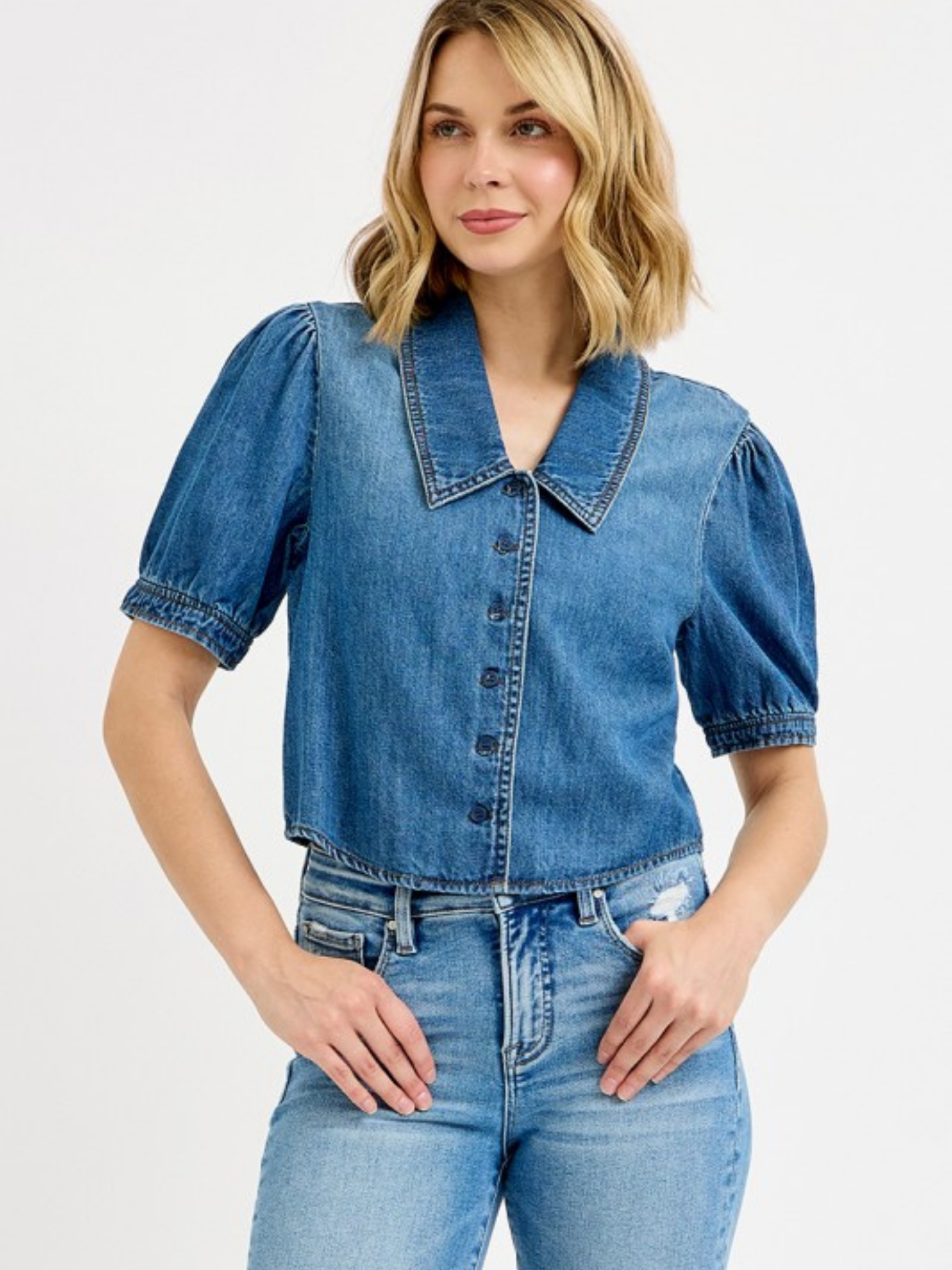 Woman wearing a denim shirt and jeans on a light gray background