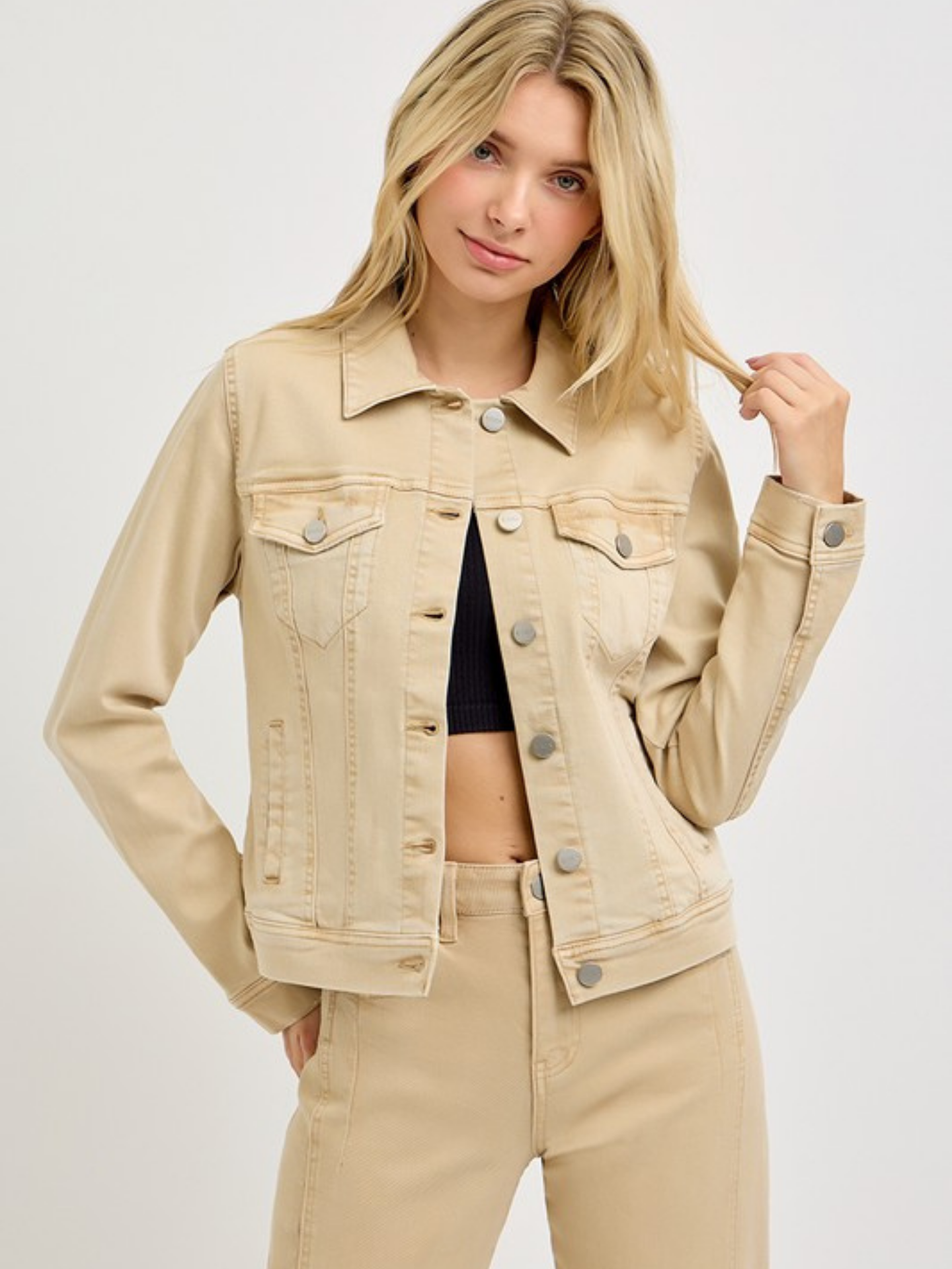 Woman wearing a beige denim jacket on a plain background