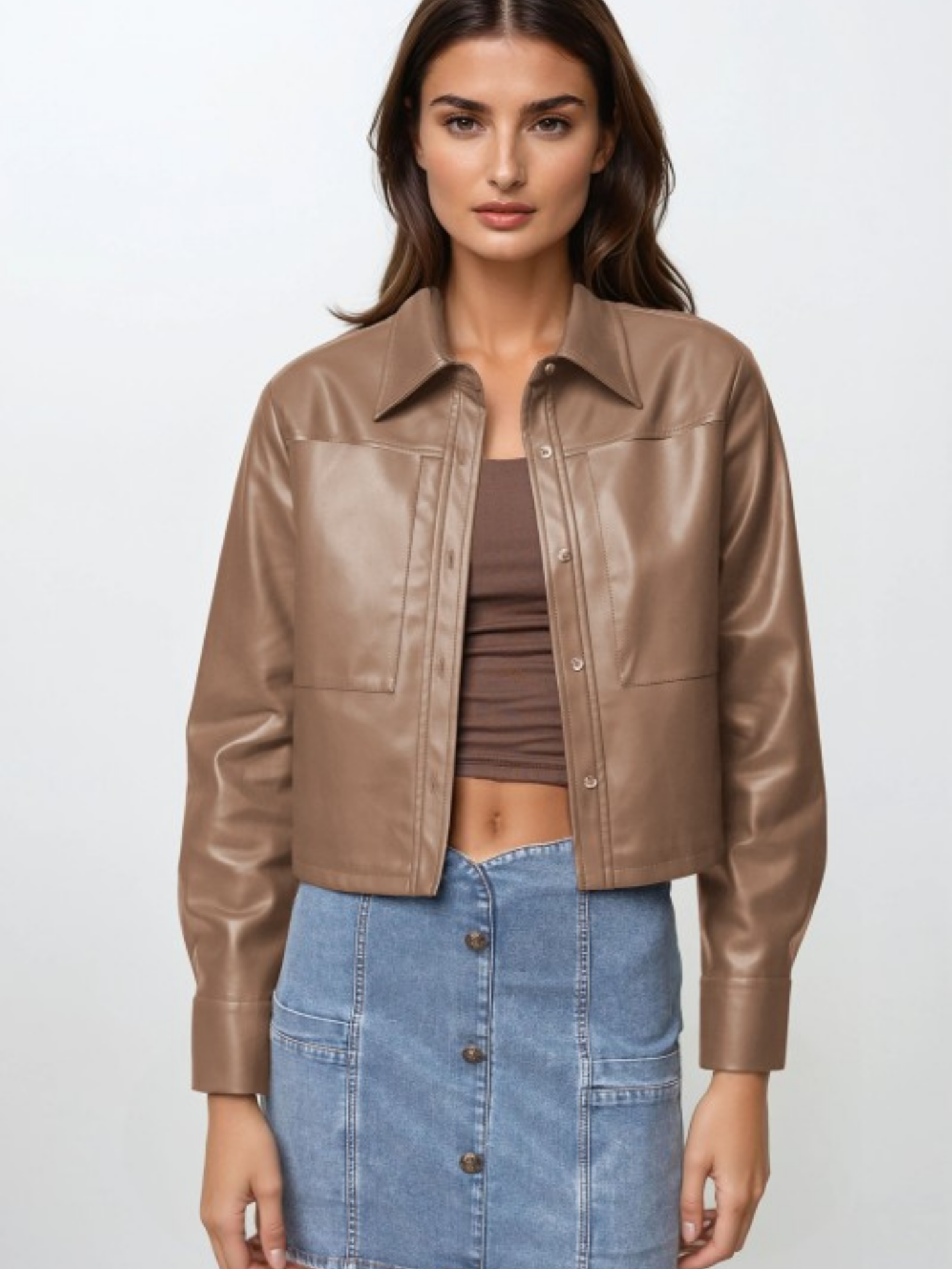 Woman wearing a brown leather jacket and blue denim skirt on a white background