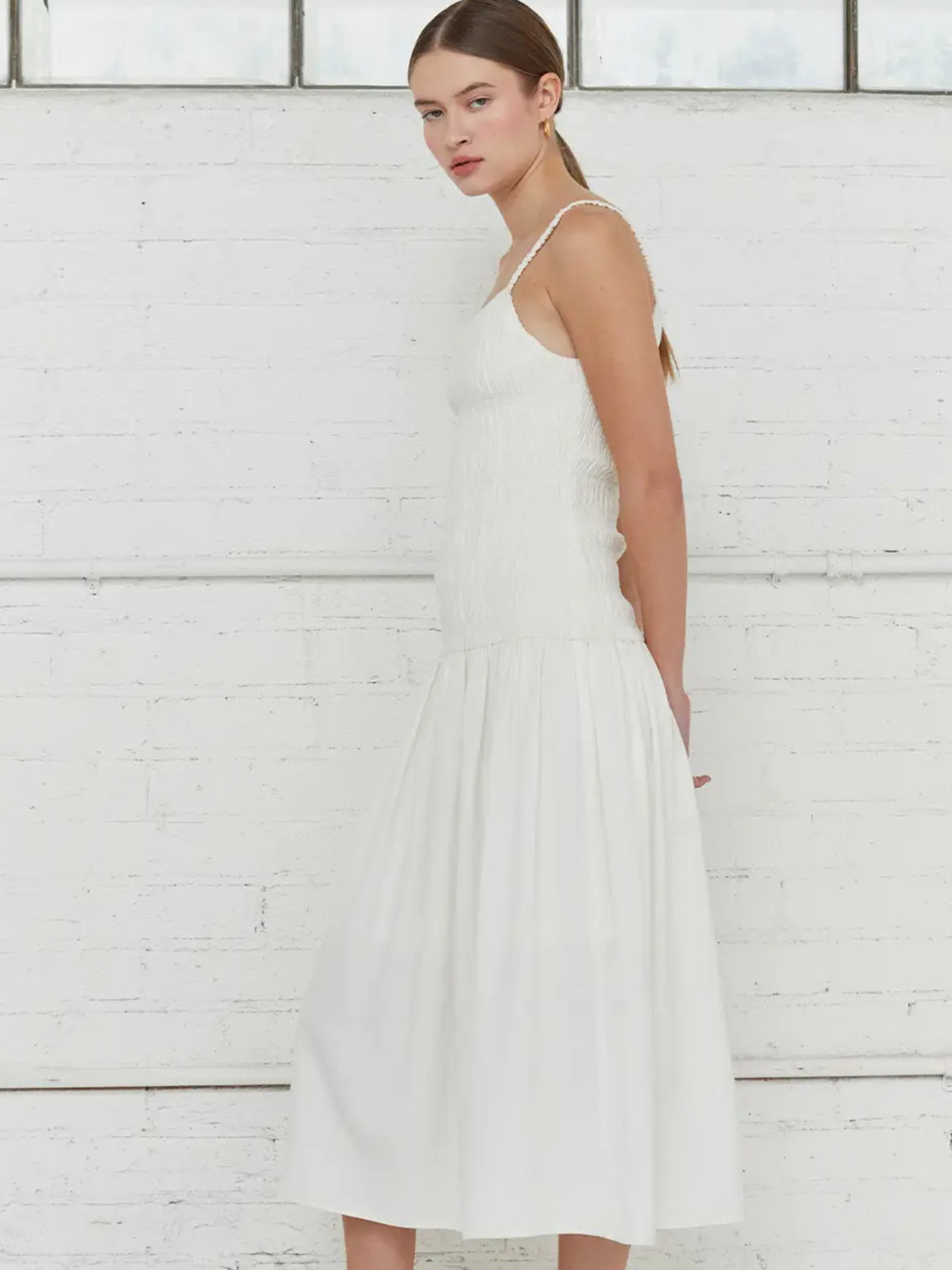White Crescent smocked body dress shown on a model, showcasing the fitted bodice and stylish design, perfect for casual or dressy occasions.